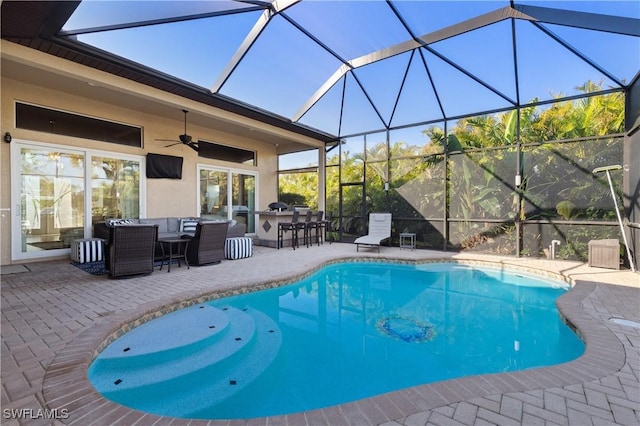 pool featuring glass enclosure, a patio, ceiling fan, outdoor dry bar, and an outdoor hangout area