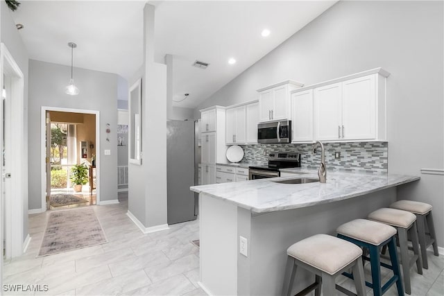 kitchen with a breakfast bar area, stainless steel appliances, kitchen peninsula, and white cabinets