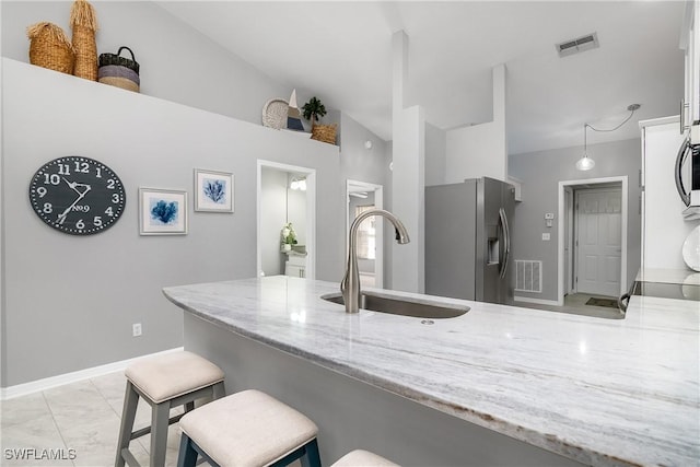 kitchen featuring appliances with stainless steel finishes, lofted ceiling, sink, a kitchen bar, and kitchen peninsula