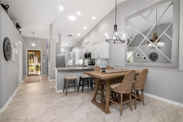 kitchen with stainless steel appliances, a kitchen breakfast bar, tasteful backsplash, white cabinets, and decorative light fixtures