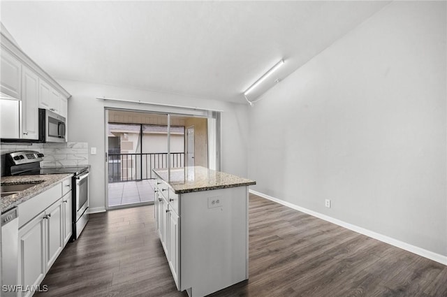 kitchen featuring light stone countertops, white cabinetry, stainless steel appliances, and a center island