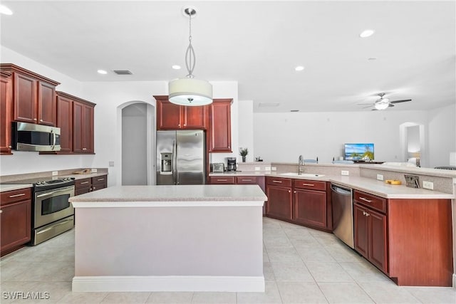 kitchen with pendant lighting, light countertops, appliances with stainless steel finishes, a kitchen island, and dark brown cabinets