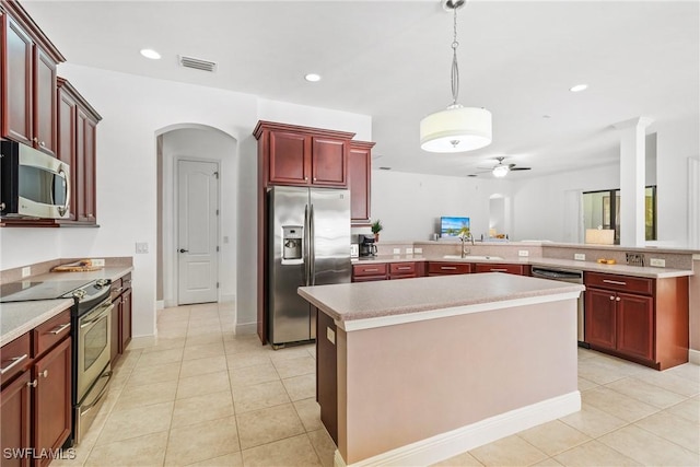 kitchen featuring arched walkways, visible vents, a kitchen island, stainless steel appliances, and light countertops