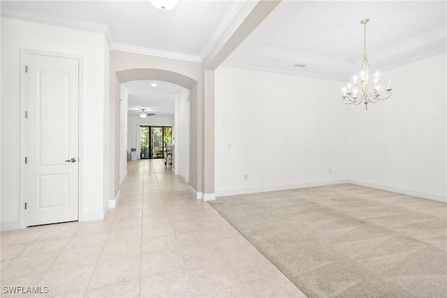 interior space with light tile patterned floors, arched walkways, light colored carpet, ornamental molding, and an inviting chandelier