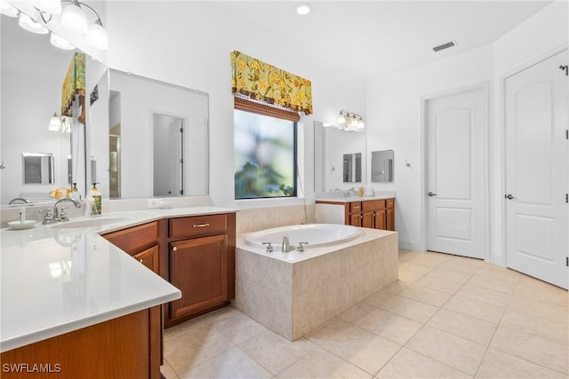 bathroom with visible vents, two vanities, a sink, tile patterned flooring, and a bath