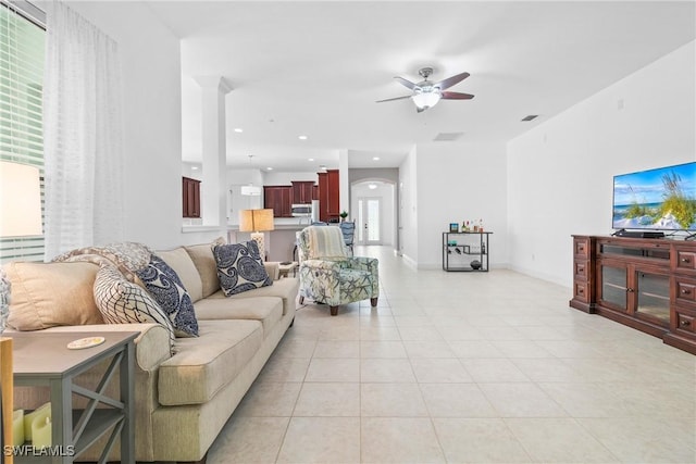 living area with light tile patterned floors, arched walkways, baseboards, ceiling fan, and recessed lighting