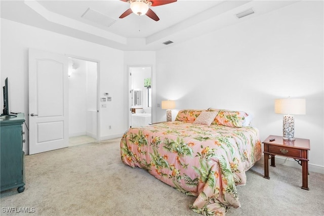 carpeted bedroom with ensuite bath, visible vents, a tray ceiling, and baseboards