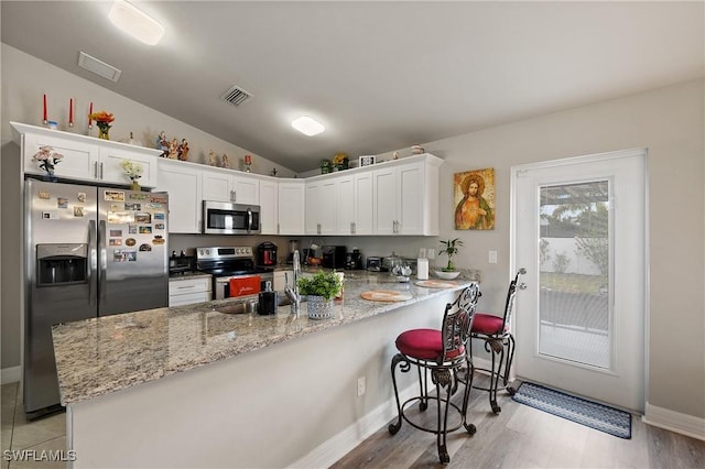 kitchen featuring sink, white cabinetry, vaulted ceiling, kitchen peninsula, and stainless steel appliances