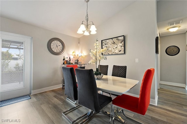 dining space featuring a notable chandelier, vaulted ceiling, and wood-type flooring