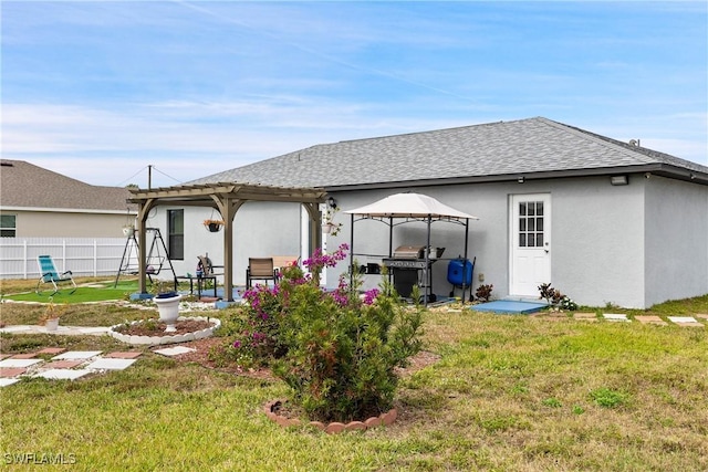 rear view of property featuring a pergola, a yard, and a gazebo