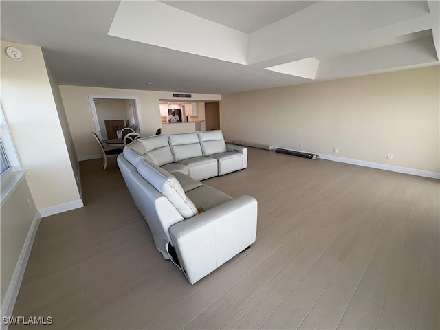 living room with a tray ceiling and light hardwood / wood-style flooring