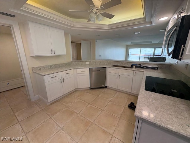 kitchen with stainless steel dishwasher, a raised ceiling, and white cabinets