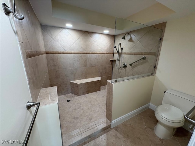 bathroom featuring tile patterned flooring, toilet, and tiled shower