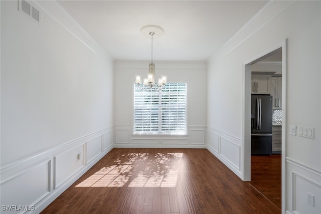 unfurnished dining area featuring dark hardwood / wood-style flooring, ornamental molding, and a chandelier