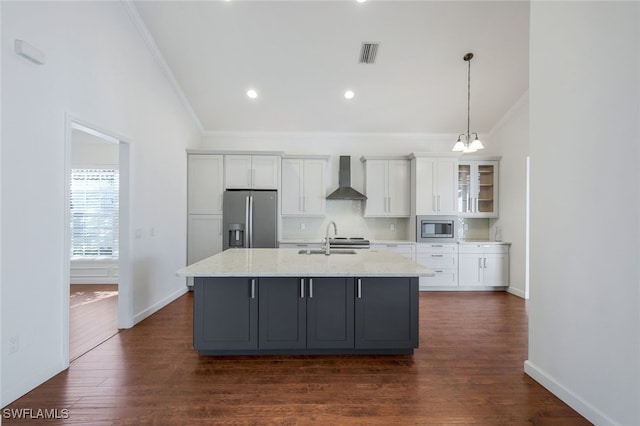 kitchen with white cabinetry, stainless steel appliances, sink, and wall chimney range hood