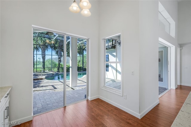 doorway featuring a notable chandelier, wood-type flooring, and a high ceiling