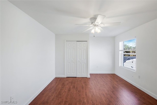 unfurnished bedroom with dark hardwood / wood-style flooring, a closet, and ceiling fan