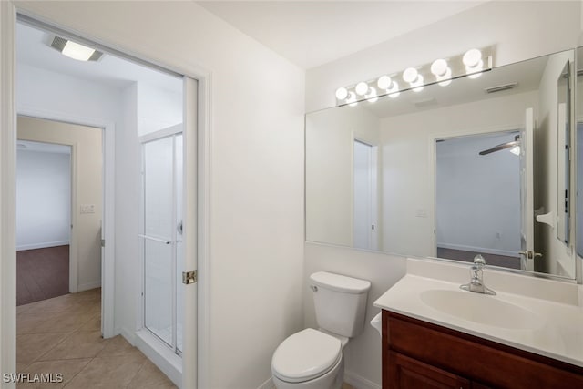 bathroom with a shower with door, vanity, tile patterned floors, and toilet