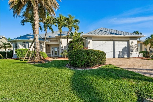 ranch-style home featuring a garage, french doors, and a front lawn