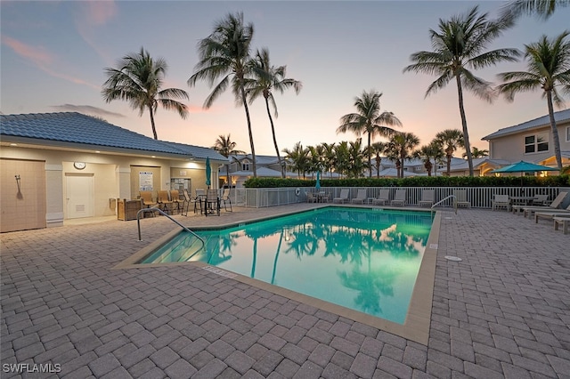 pool at dusk with a patio area