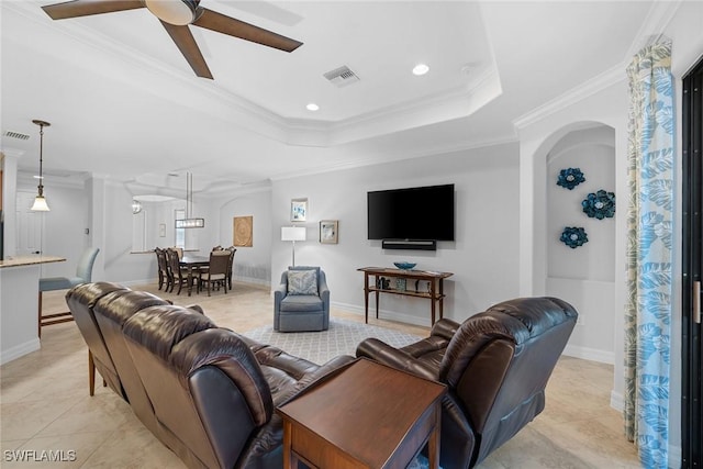 living room featuring crown molding, light tile patterned floors, a tray ceiling, and ceiling fan