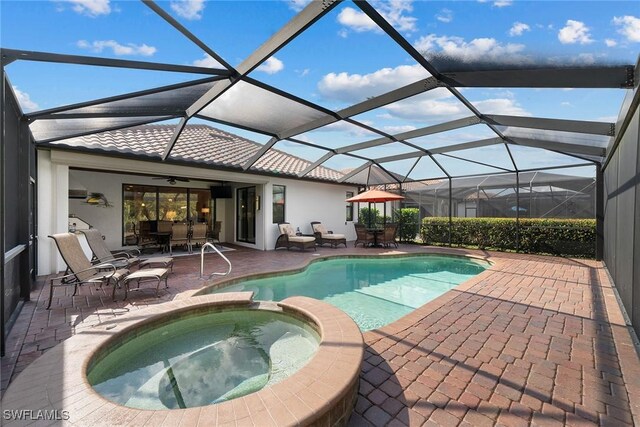 view of pool featuring an in ground hot tub, glass enclosure, and a patio