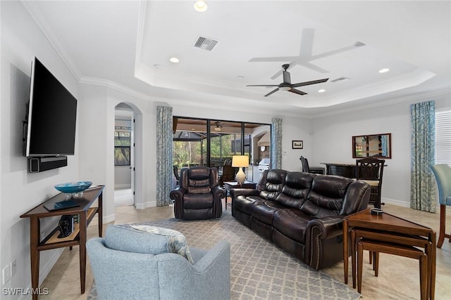 tiled living room with crown molding, a tray ceiling, and ceiling fan