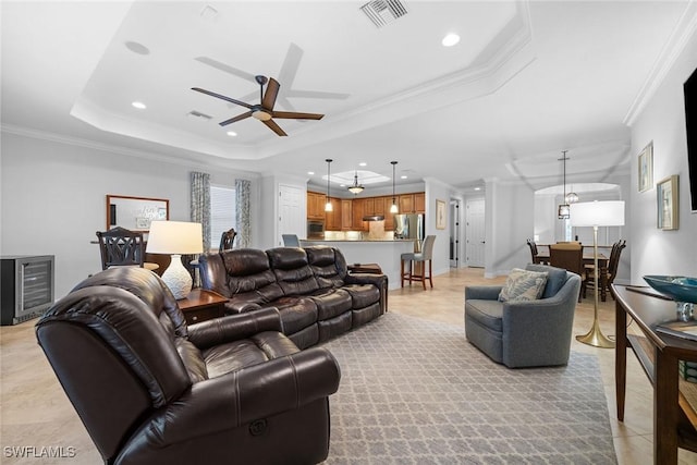 tiled living room featuring a raised ceiling, ornamental molding, beverage cooler, and ceiling fan