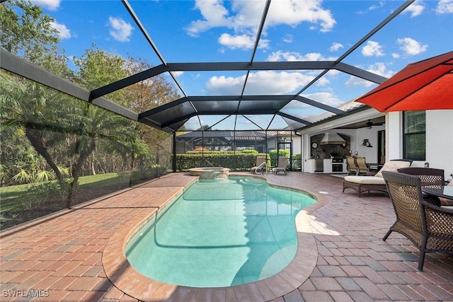 view of pool with a patio area, a lanai, an in ground hot tub, ceiling fan, and exterior kitchen