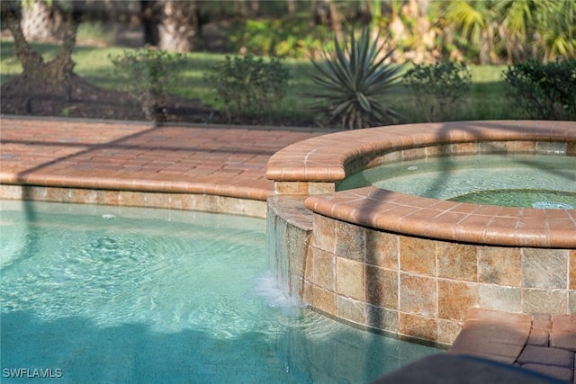 view of swimming pool with pool water feature and an in ground hot tub