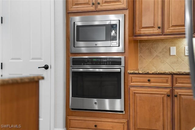 kitchen featuring light stone counters, stainless steel appliances, and decorative backsplash