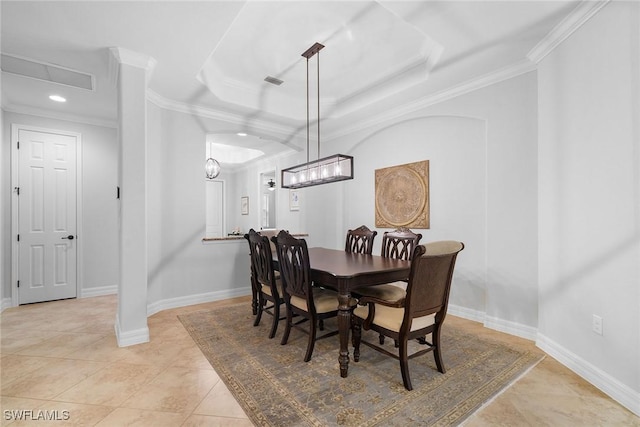 tiled dining space featuring ornamental molding and a tray ceiling