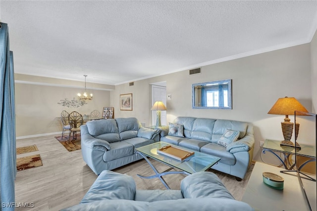 living room featuring ornamental molding, a chandelier, a textured ceiling, and light hardwood / wood-style floors