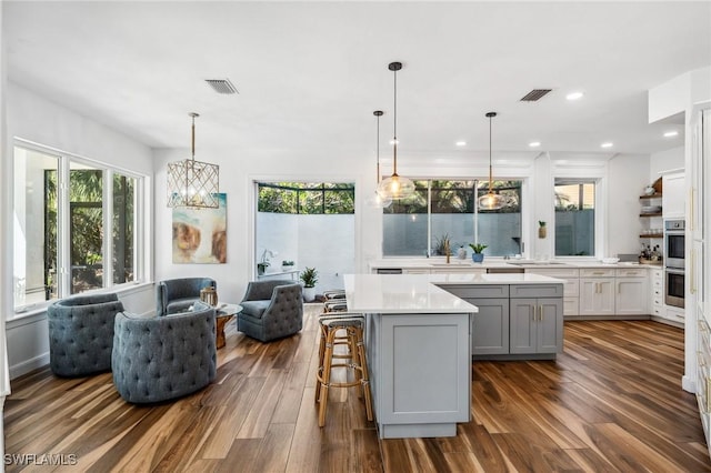 kitchen with a breakfast bar, plenty of natural light, a center island, and hanging light fixtures