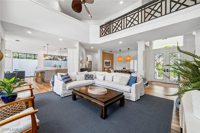 living room featuring ornate columns, a high ceiling, hardwood / wood-style floors, and french doors