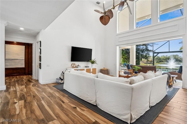 living room featuring hardwood / wood-style flooring, ceiling fan, and a high ceiling