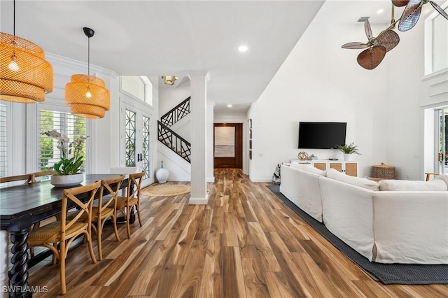 living room with decorative columns, a towering ceiling, hardwood / wood-style floors, and ceiling fan