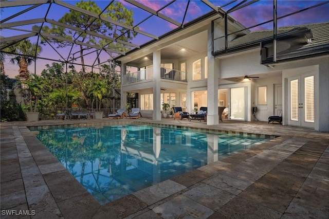 pool at dusk with a patio area, ceiling fan, and glass enclosure