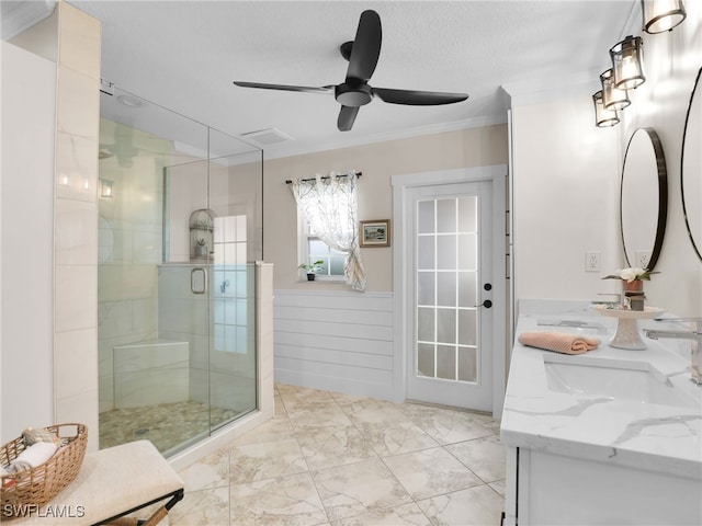 bathroom featuring vanity, ornamental molding, ceiling fan, walk in shower, and a textured ceiling