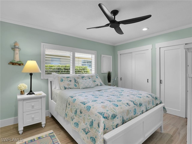 bedroom featuring light wood-type flooring, multiple closets, ornamental molding, and ceiling fan