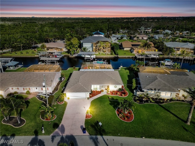 aerial view at dusk with a water view and a residential view