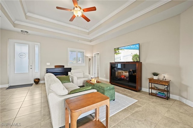 tiled living room featuring a raised ceiling, crown molding, and ceiling fan