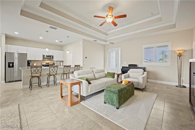 tiled living room with crown molding, a raised ceiling, and ceiling fan