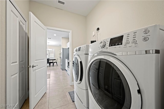 clothes washing area with washing machine and dryer and light tile patterned floors