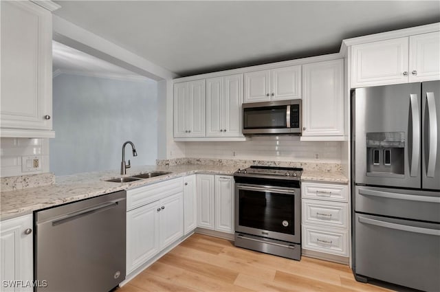 kitchen featuring white cabinetry, stainless steel appliances, sink, and light hardwood / wood-style flooring