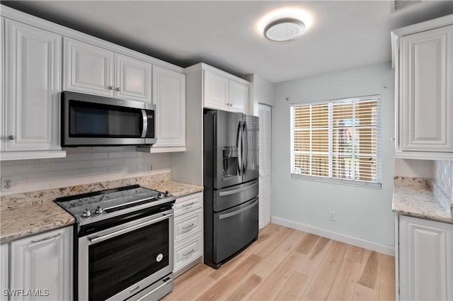 kitchen with white cabinetry, light stone counters, decorative backsplash, and stainless steel appliances