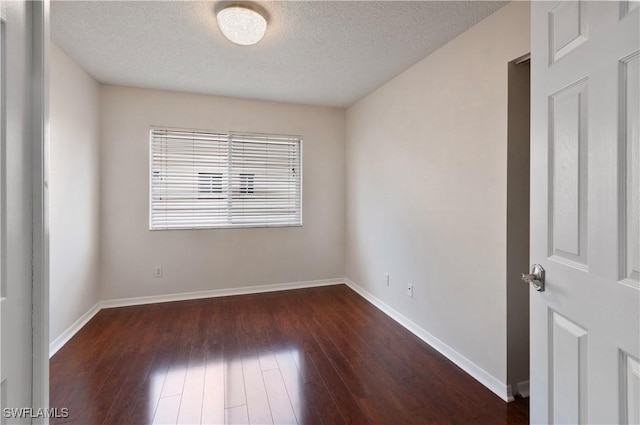 empty room with dark wood-type flooring and a textured ceiling