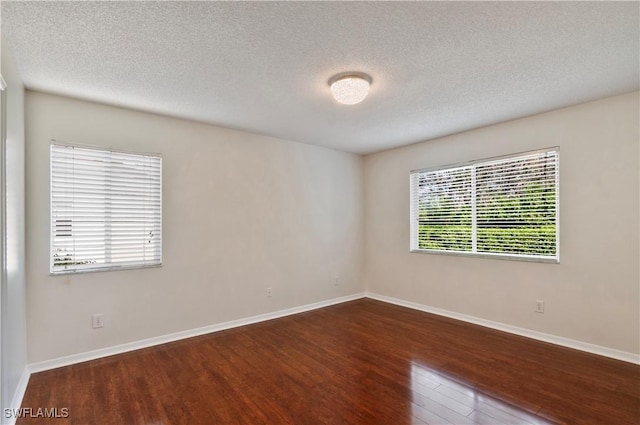 unfurnished room with dark wood-type flooring and a textured ceiling