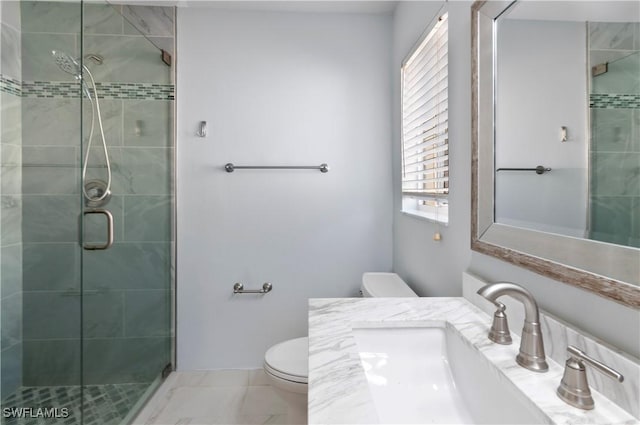 bathroom featuring a shower with door, vanity, and toilet