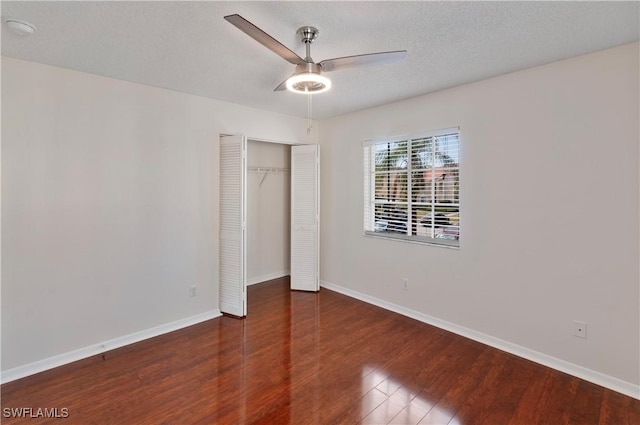 unfurnished bedroom featuring ceiling fan, dark wood-type flooring, a textured ceiling, and a closet